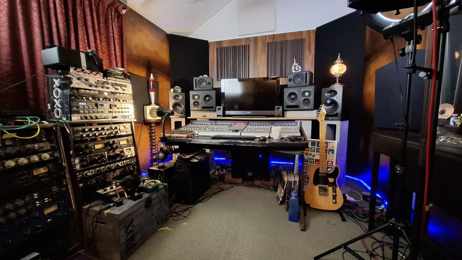 The sHOWpONY studio: rack gear and a red curtain, a mixing desk with monitors, a lava lamp, a Telecaster leaning on the desk